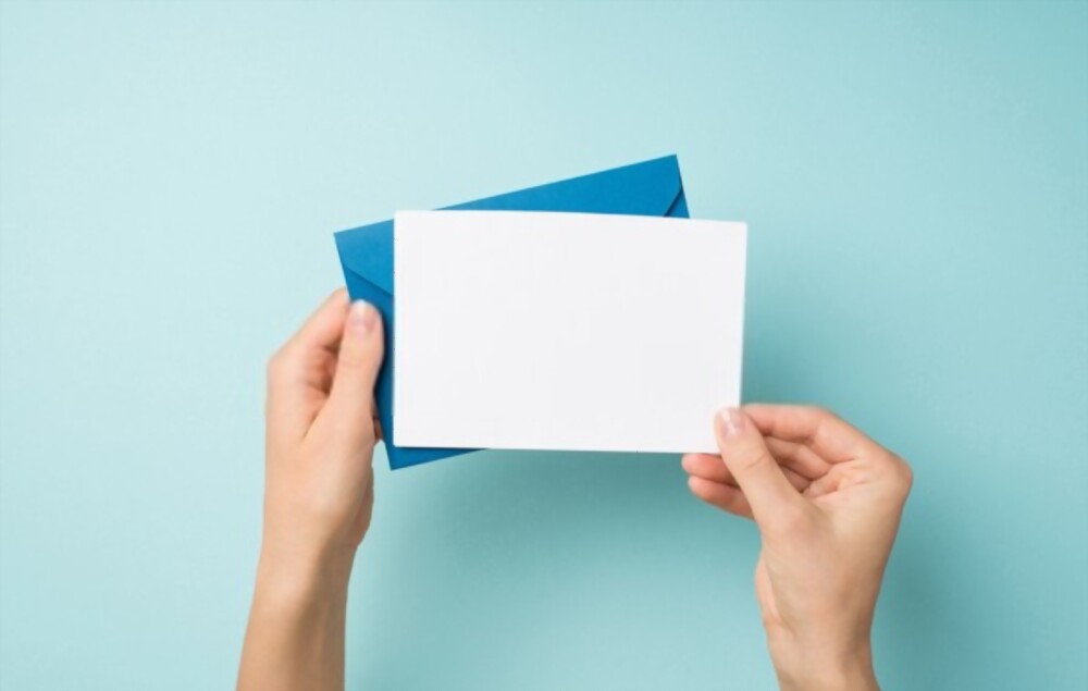 Hand holding an envelope and white card